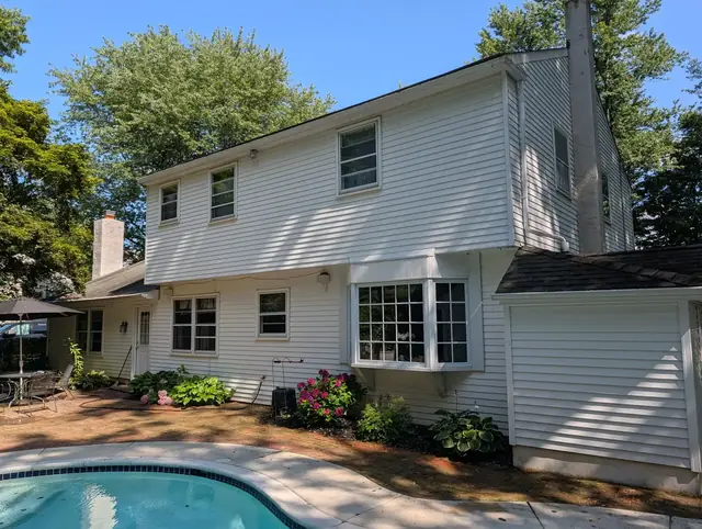 Freshly washed white siding on a home with a backyard pool